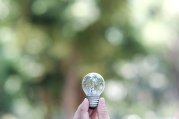 Poster - businessman holding a glowing light bulb on bokeh background