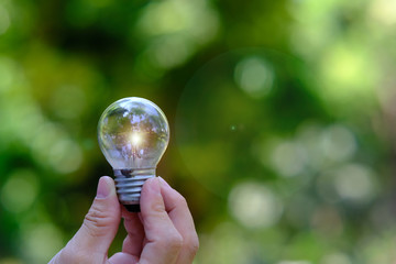 Poster - businessman holding a glowing light bulb on bokeh background