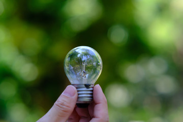 Poster - businessman holding a glowing light bulb on bokeh background