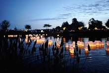 Burning Candles Floating On Lake At Dusk