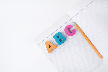 Wall Mural - A B C Multicolored wooden letters alphabet on a paper book with orange pencil on white background. Education, Examination, Test, Quiz, Choice for Answer 