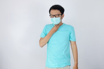 Wall Mural - Young Asian man having sore throat and touching his neck with wearing medical mask.