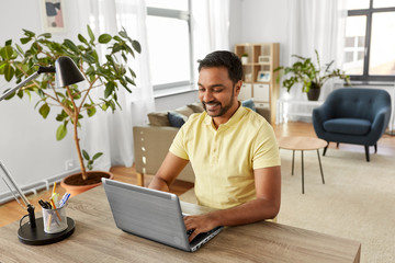 Poster - technology, remote job and lifestyle concept - happy indian man with laptop computer working at home office