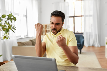 Poster - technology, remote job and lifestyle concept - happy indian man with laptop computer celebrating success at home office