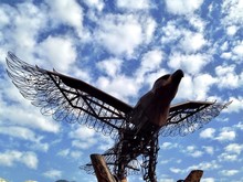 Low Angle View Of Animal Sculpture Against Cloudy Sky