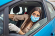 © Dragana Gordic - Woman during pandemic isolation at city, she is in car. Woman in protective mask driving a car on road. Young woman with protective mask and gloves driving a car.