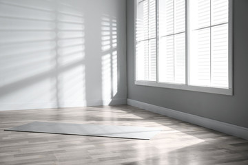 Unrolled grey yoga mat on floor in room