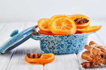 Slices of dried oranges or tangerines with anise and cinnamon in a blue bowl on a light background. Vegetarianism and healthy eating