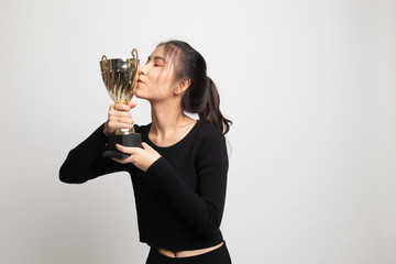 Successful young asian woman holding kissing a trophy.