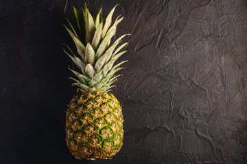 Fresh sweet pineapple on dark black textured background, top view copy space