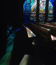 Side View Of Empty Benches Against Stained Glass At Church
