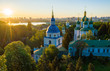 Golden and green domes of orthodox church in the middle of autumn park. Famous building is blurred.