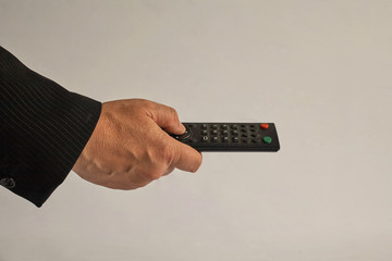 Hand holds the remote control from the TV. Hand finger presses the button.