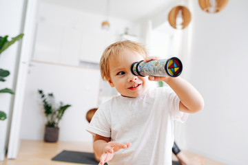 Little boy looking into kaleidoscope. Blurred. Focus on a boy. At home