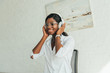 © LIGHTFIELD STUDIOS - happy african american girl in eyeglasses touching wireless headphones while listening music