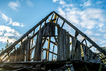 ruined roof of an old house on a background of a pigeon sky with sun glare