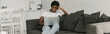© LIGHTFIELD STUDIOS - horizontal image of attentive african american freelancer working on laptop on sofa in kitchen