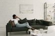 © LIGHTFIELD STUDIOS - pensive african american freelancer resting on sofa near table with notebook in living room