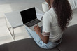 © LIGHTFIELD STUDIOS - high angle view of african american girl using laptop with blank screen and holding coffee cup