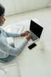 © LIGHTFIELD STUDIOS - high angle view of african american freelancer using laptop with blank screen near smartphone and empty cup