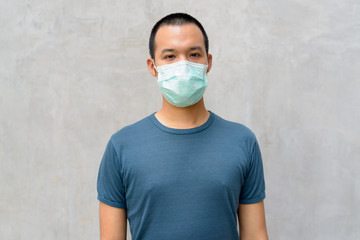 Wall Mural - Young Asian man with mask for protection from corona virus outbreak outdoors
