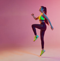 Athletic cool girl trainer teaches group crossfit and work out online training on a bright neon background.