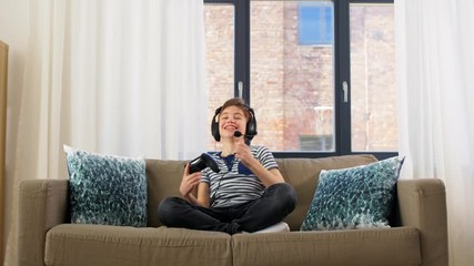 Sticker - leisure, children, technology and people concept - happy boy in headphones with microphone and gamepad playing video game and celebrating success at home