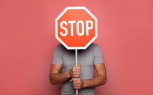 It's Time To Stop. Close-up Photo Of A Young Strong Man, Who Is Hiding Behind A Stop Road Sign, While Holding It In His Hands.