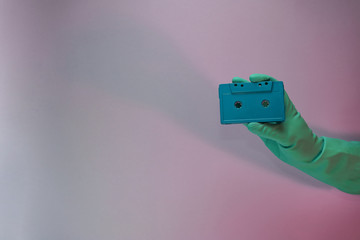 Poster - Green Hand holding audio cassette tape in the color light. Beautiful minimal in neon light. Minimalism retro style concept. Background pattern for design.