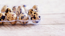 Quail Eggs On Wooden Background In Transparent Packaging
