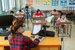 © visoot - Teacher wearing protective mask to Protect Against Covid-19,Group of school kids with teacher sitting in classroom online and raising hands,Elementary school,Learning and people concept.