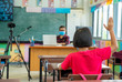 © visoot - School kids wearing protective mask to Protect Against Covid-19,Group of school kids with teacher sitting in classroom online and raising hands,Elementary school,Learning and people concept.