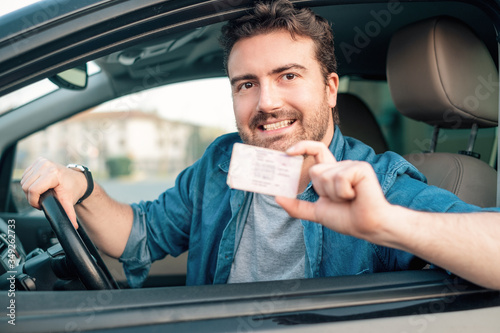 Fotografía Cheerful man holding driver license in his car