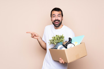 Wall Mural - Man holding a box and moving in new home over isolated background surprised and pointing finger to the side