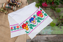 Handmade Embroidery Towel On A Vintage Wooden Table With Geranium Flower And Ceramic Jugs