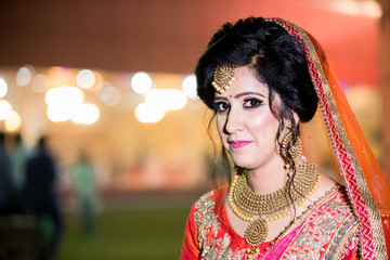 Beautiful  Indian bride dressed in Orange traditional wedding clothes  with negative space on left 