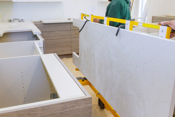 Workers lifting and installing with maple granite counter in kitchen