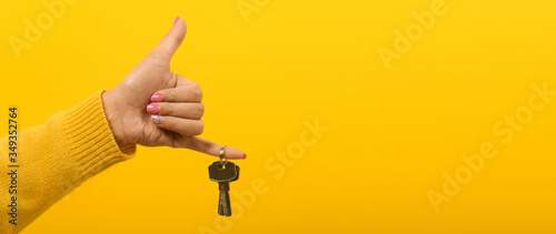 Fotografía hand holding house keys over yellow background, panoramic mock-up