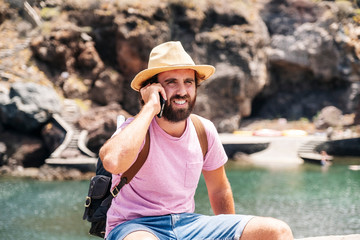 A tourist man with hat and backpack uses the mobile phone in a coastal town El Hierro, Canary Islands