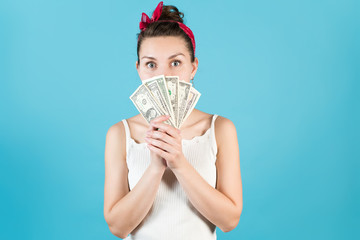 A young woman peeks out for the dollars she holds in front of her