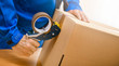 © Milan - Worker hands holding packing machine and sealing cardboard or paper boxes