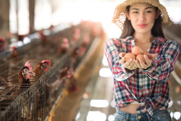 Asian farmers in the farm raise chickens and sell eggs. An Asian woman is carrying eggs and is happy to order and sell eggs online.