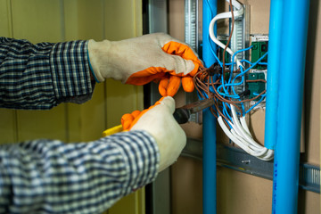 Aufkleber - Young repairman fixing electrical,Electrician checking wires in electrical box with pliers in corridor of a residential electrical system.