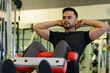 © Ranta Images - Full body shot of young bearded Indian man doing sit ups at the gym