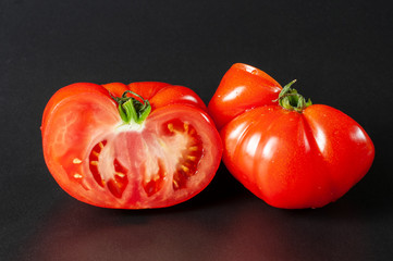 halved red beef tomato on dark background