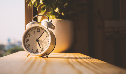 Alarm Clock on wooden in the morning with sunlight.