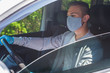 © Jurii - Quarantine concept. Pandemic. A young guy-taxi driver in a gray protective medical mask and a gray jacket is sitting behind the driver's seat in the car. He looks straight. Virus. Coronavirus. Insulat