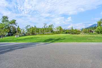 Asphalt road and green trees in the blue sky