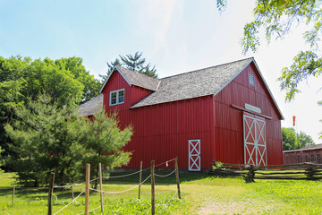 a bright red barn in the green field in a day in summer