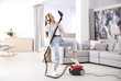 © New Africa - Young woman having fun while vacuuming at home